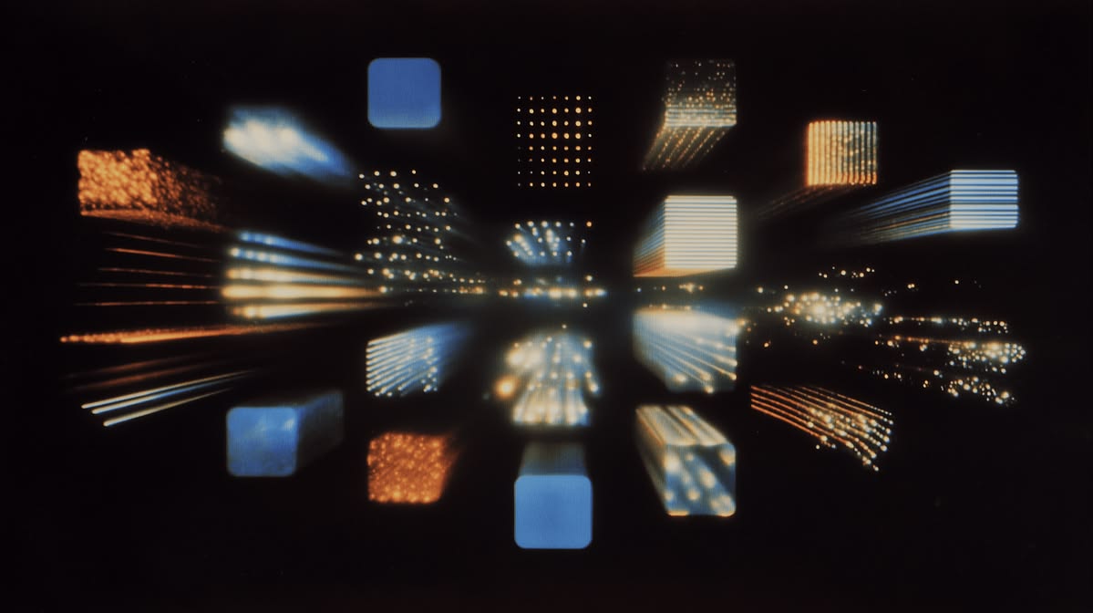 Long-exposure photograph of blue and amber light blocks streaking toward a dark vanishing point
